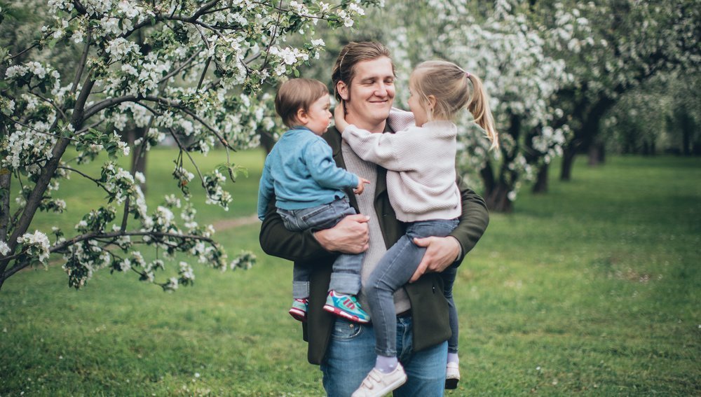 Vater mit zwei Kindern im Arm