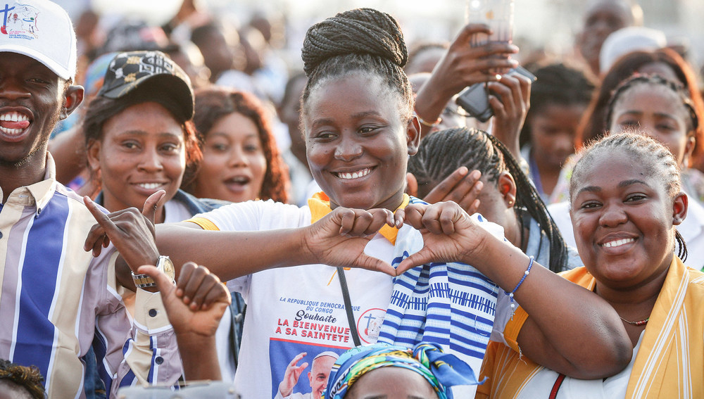 Eine Frau steht in der Menschenmenge und formt mit den Händen ein Herz in Erwartung von Papst Franziskus am 1. Februar 2023 auf dem Flughafen Ndolo in Kinshasa (Demokratische Republik Kongo).