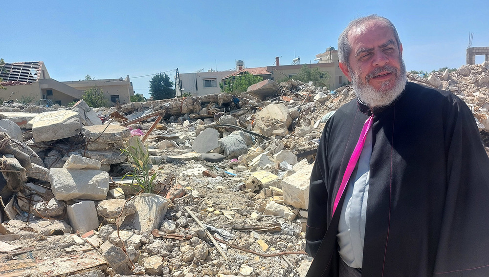 Priester vor zerstörtem Gebäude in Alma Sha'b