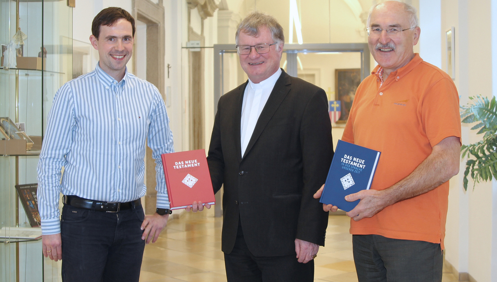 Franz Kogler und Reinhard Stiksel vom Bibelwerk Linz übergeben das Buch 'Das Neue Testament. Übertragen in die Sprache unserer Zeit' an Bischof Manfred Scheuer