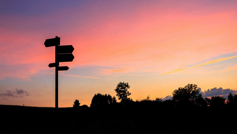 Straßenschilder vor rötlichem Abendhimmel