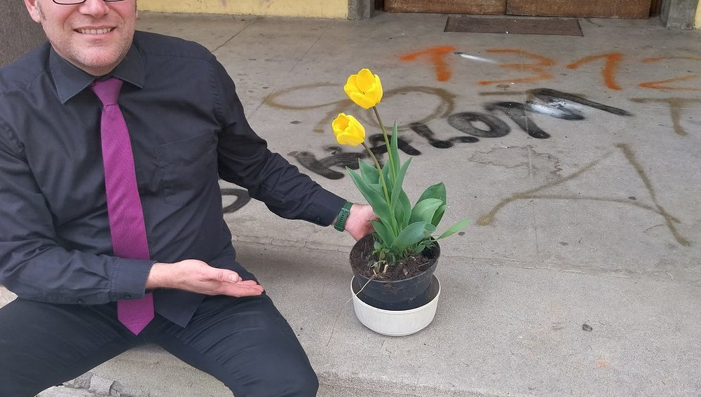 Pfarrer Paul Nitsche vor der beschmierten Kreuzkirche mit den ersten Blumen