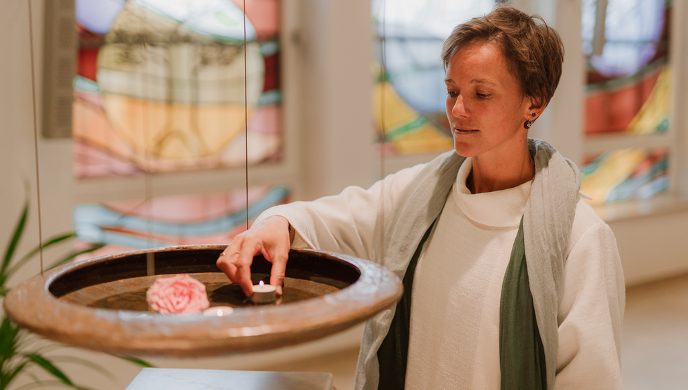 Margot Brucker, Krankenhaus-Seelsorgerin im Klinikum Grieskirchen, setzt eine Kerze in ein Wasserbecken.